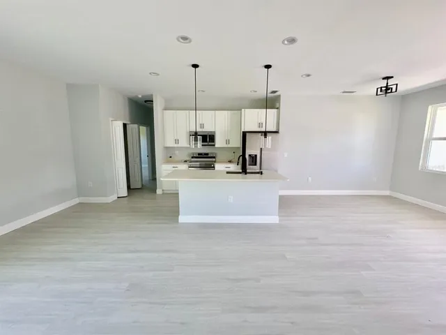 a view of a kitchen with stainless steel appliances a refrigerator a sink dishwasher with wooden floor