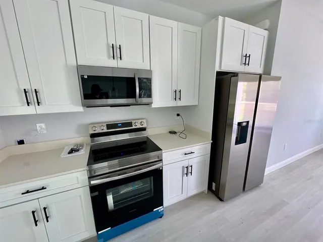 a kitchen with white cabinets and stainless steel appliances