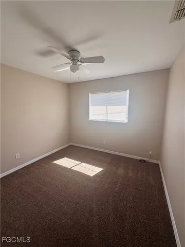 an empty room with a window and a ceiling fan