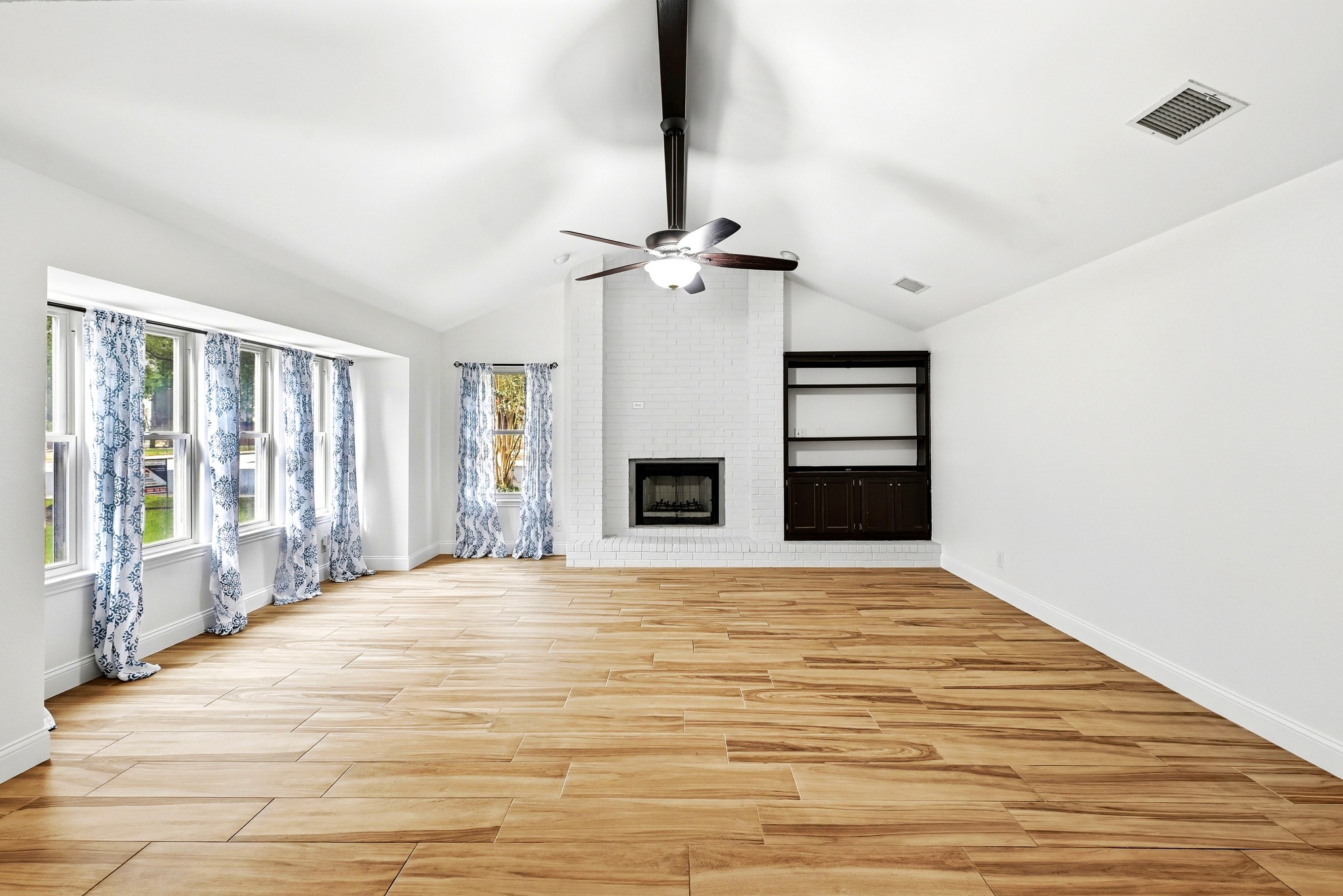 11218 Stormy Ridge Road Austin, TX 78739 - Photo 6 of 38 An inviting fireplace anchor this airy space beneath soaring vaulted ceilings and wood-look tile flooring.