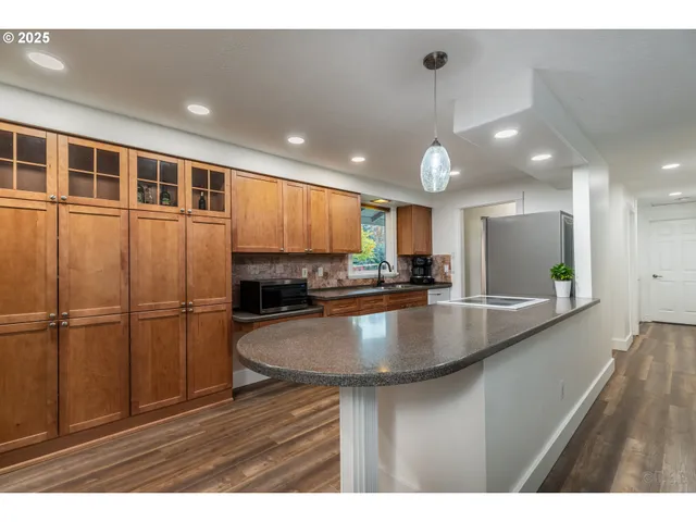 a kitchen with stainless steel appliances granite countertop a sink a refrigerator and a granite counter tops