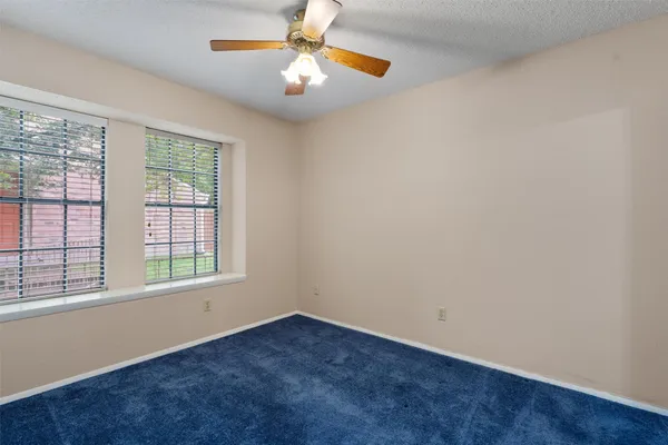 an empty room with a window and a fan
