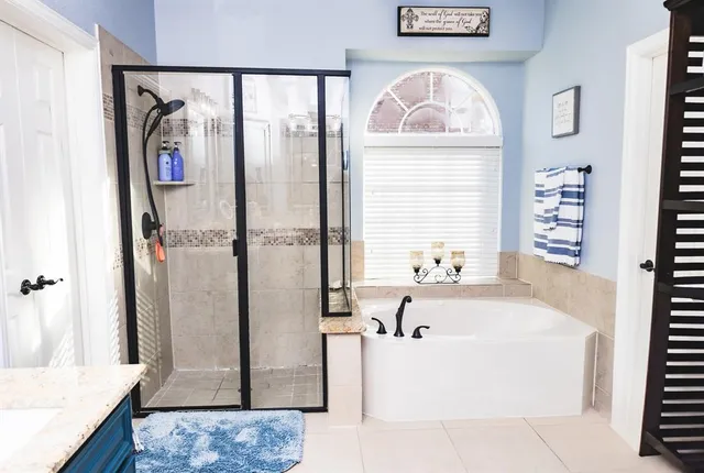 a bathroom with a tub a rug and a window