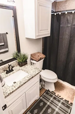 a bathroom with a granite countertop toilet sink and mirror