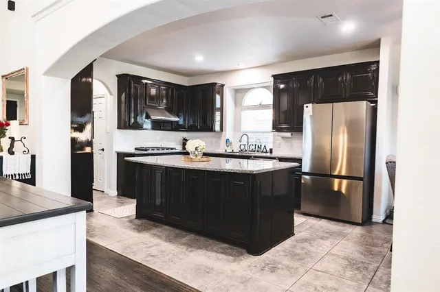 a kitchen with stainless steel appliances granite countertop a refrigerator a stove and a sink with wooden cabinets