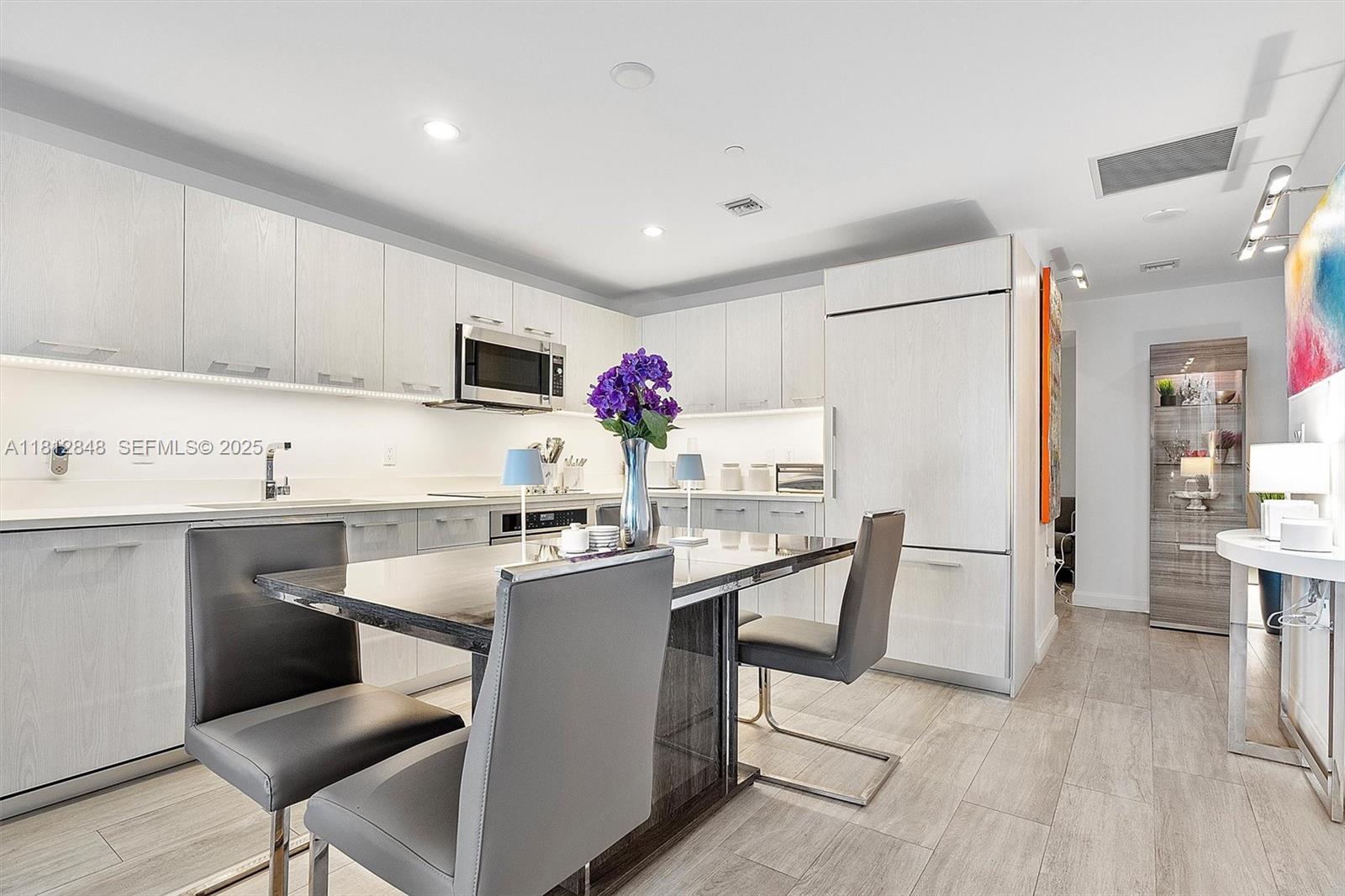 55 Southwest 9th Street, Unit 1510 Miami, FL 33130 - Photo 10 of 46 a kitchen with kitchen island a sink stove and white cabinets