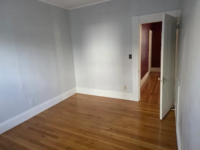 a view of an empty room with wooden floor and closet