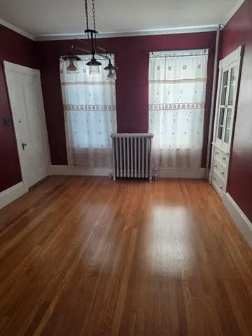 a view of empty room with wooden floor and window
