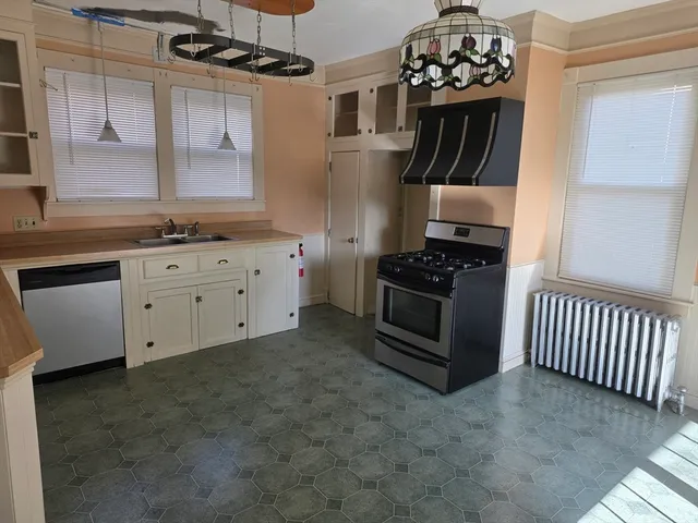 a kitchen with granite countertop a stove a sink and a refrigerator