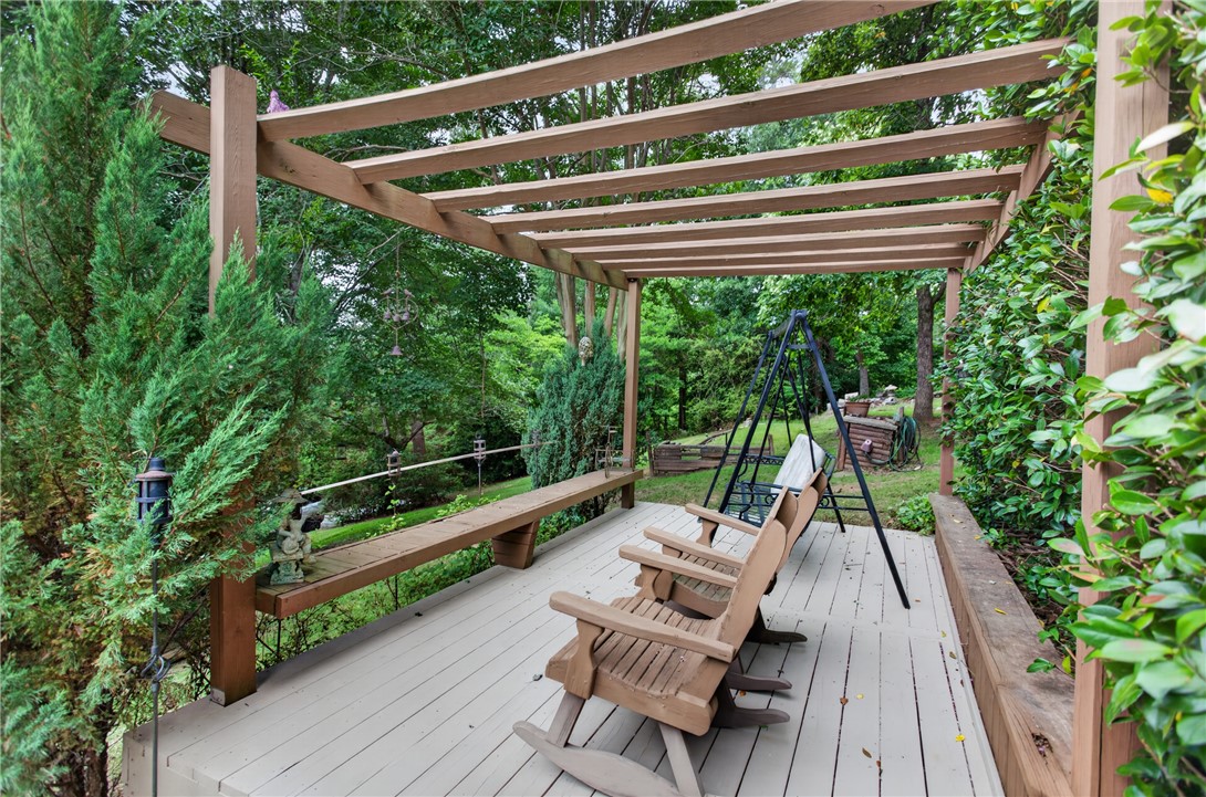 351 River Road Westminster, SC 29693 - Photo 43 of 50 An inviting deck, shaded by a wooden pergola, offers a private outdoor retreat amidst verdant surroundings.