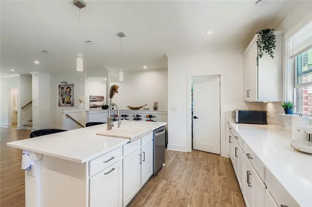 a large white kitchen with a stove a sink a refrigerator and a dining table with wooden floor