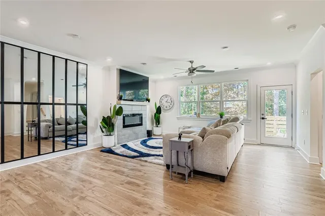 a living room with furniture large windows and wooden floor