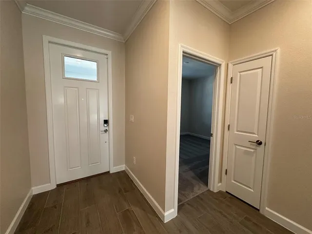 a view of an empty room with wooden floor and a bathroom