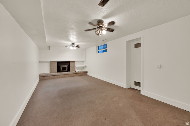 360 400 North Centerville, UT 84014 - Photo 30 of 30 Spacious room featuring a stone fireplace with hearth, integrated shelving, three ceiling fans, and a window