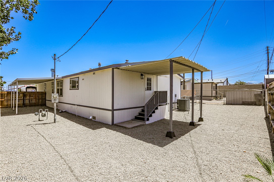 273 Aztec Lane Henderson, NV 89015 - Photo 28 of 28 A neatly maintained mobile home with a covered patio, set on a gravel lot under a clear sky.