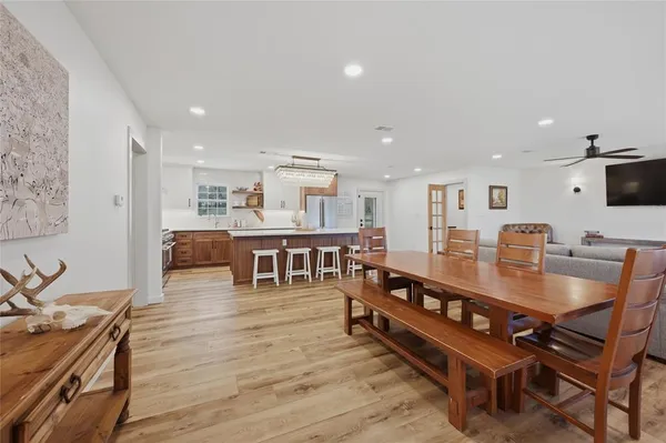 a room with stainless steel appliances kitchen island granite countertop a table chairs and a refrigerator
