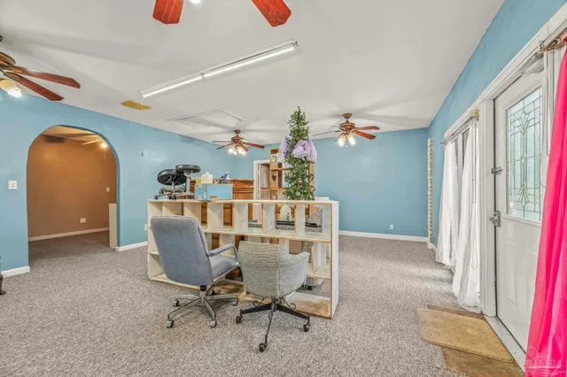 an empty room with chandelier fan and windows