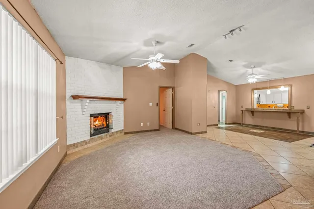 an empty room with fireplace and a ceiling fan