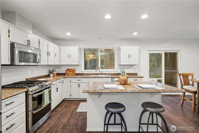 a kitchen with granite countertop white cabinets and stainless steel appliances