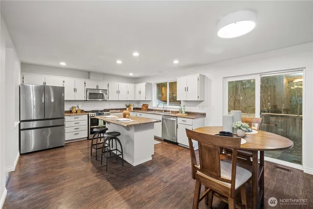 a kitchen with a dining table chairs refrigerator and cabinets