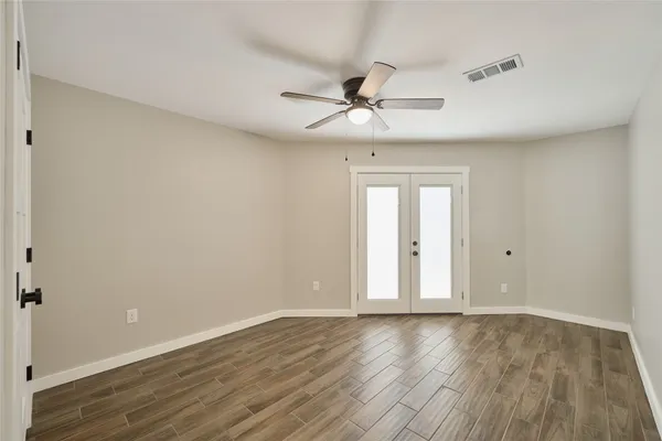 a view of an empty room with wooden floor and a window