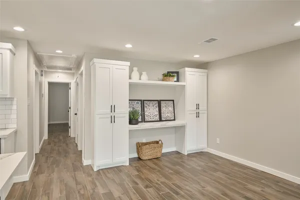 a view of a hallway with wooden floor and a bathroom