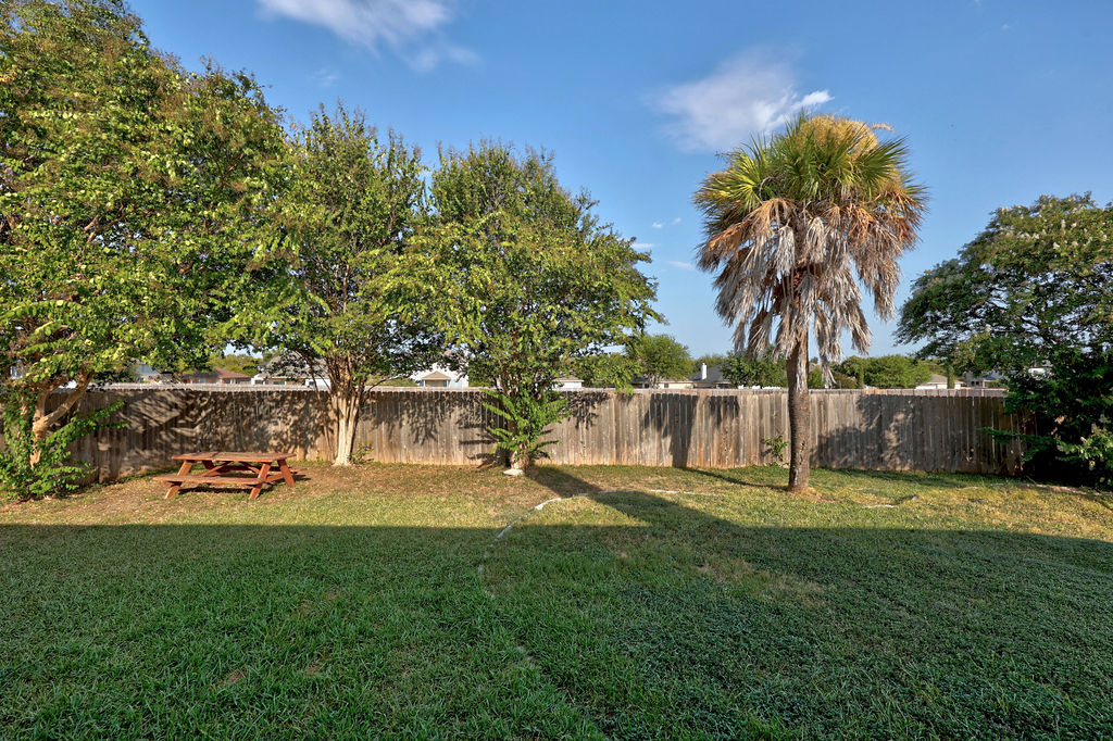 400 Ranier Lane Round Rock, TX 78665 - Photo 32 of 36 Mature trees and a sturdy wood fence frame this level, grassy backyard retreat.