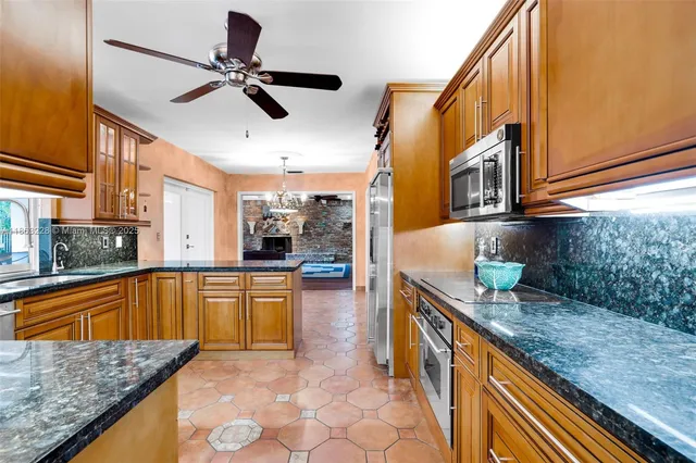 a kitchen with stainless steel appliances granite countertop a sink a stove and a refrigerator