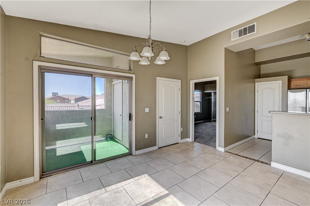 8985 South Durango Drive, Unit 2187 Las Vegas, NV 89113 - Photo 31 of 73 A well-lit dining area featuring sliding glass doors and a classic chandelier.