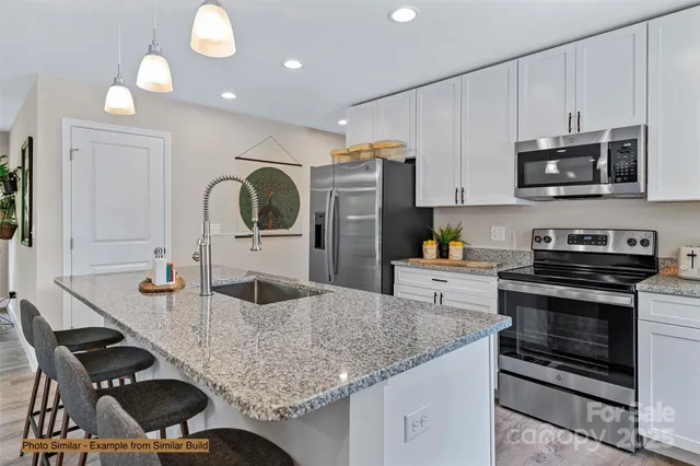 a kitchen with stainless steel appliances granite countertop a stove a sink and a microwave