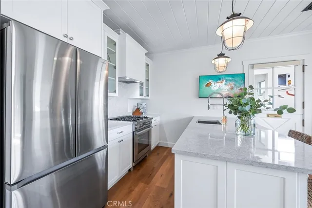 a kitchen with stainless steel appliances granite countertop a refrigerator a stove a sink dishwasher and a dining table with wooden floor