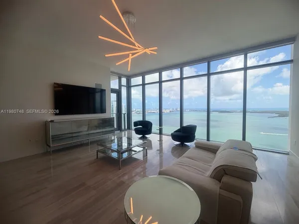 a living room with furniture tv and a floor to ceiling window