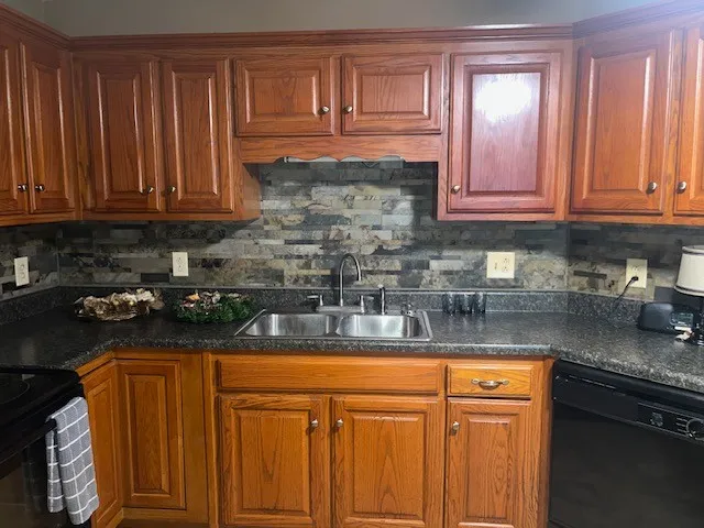 a kitchen with granite countertop stainless steel appliances stove refrigerator and cabinets