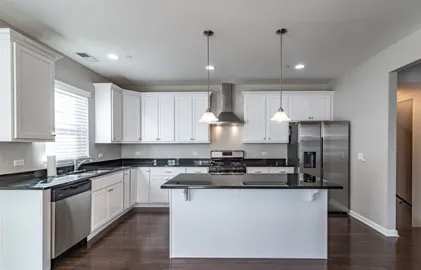 a kitchen with stainless steel appliances granite countertop a sink a stove a refrigerator cabinets and a large window