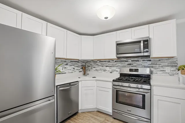 a kitchen with granite countertop cabinets stainless steel appliances and wooden floor