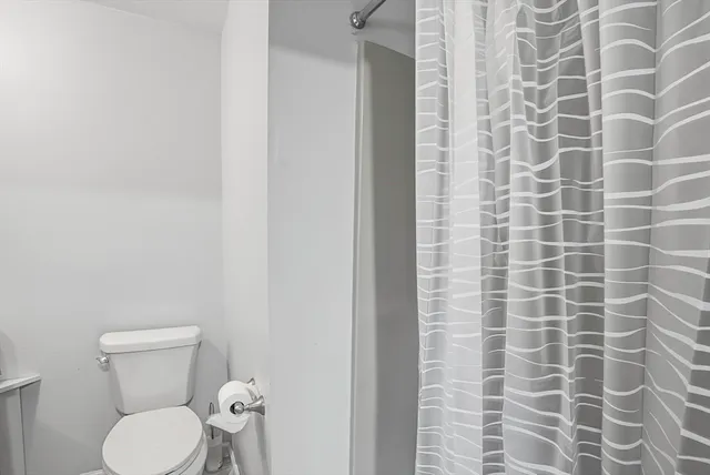 a bathroom with a toilet and a shower curtain