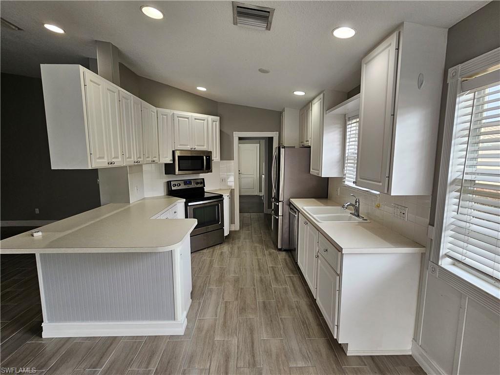 a large kitchen with stainless steel appliances sink a microwave and cabinets