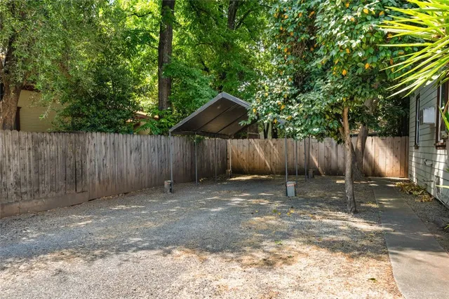 a view of a backyard with large trees and wooden fence