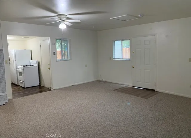 an empty room with a fan & a window