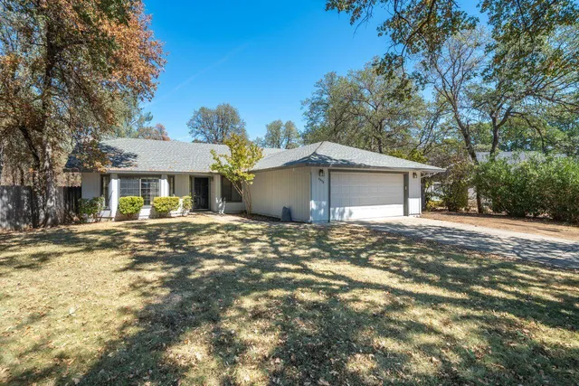 a view of a house with a yard and large tree
