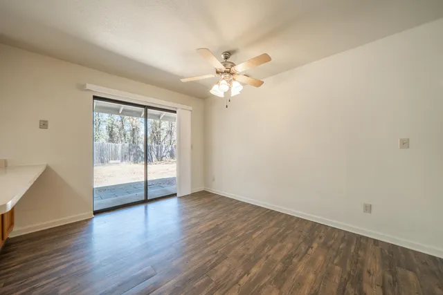 an empty room with wooden floor and fan