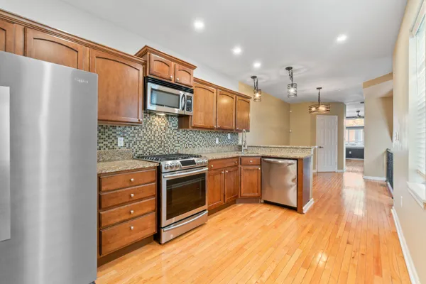a kitchen with stainless steel appliances granite countertop a refrigerator a stove and a wooden floors