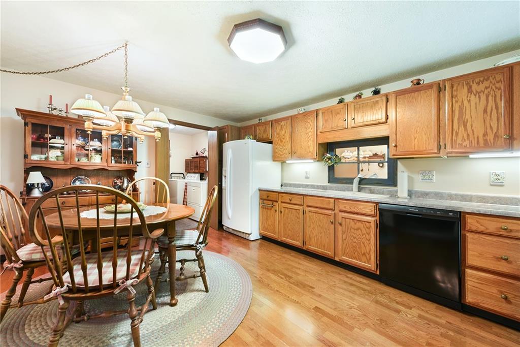 2850 Edgecliff Road, Unit 14 Lower Burrell, PA 15068 - Photo 8 of 24 a open kitchen with stainless steel appliances granite countertop a stove top oven a sink a dining table and chairs with wooden floor