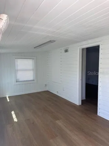 an empty room with wooden floor & windows & bathroom