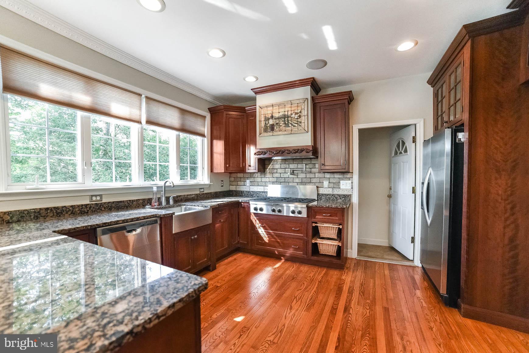 12756 Bullet Bend Road Lusby, MD 20657 - Photo 39 of 56 a kitchen with stainless steel appliances granite countertop hardwood floor sink stove large window and refrigerator