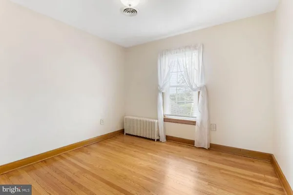 an empty room with wooden floor and window