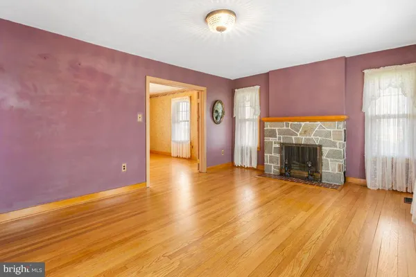 a view of empty room with wooden floor and fireplace