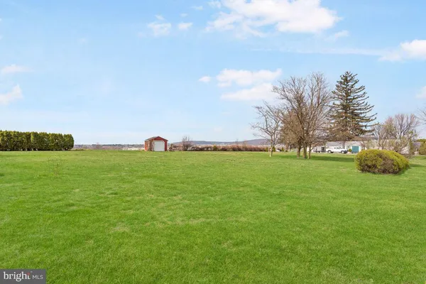 a view of a house with a big yard and large trees