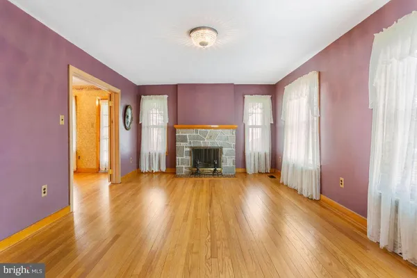 an empty room with windows a fireplace and wooden floor