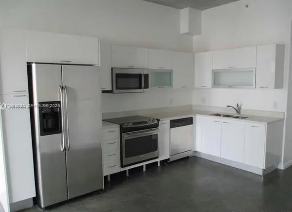 a kitchen with stainless steel appliances granite countertop a refrigerator a sink a stove and white cabinets